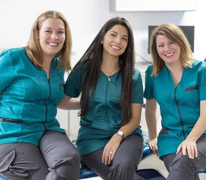 Three female dental team members smiling