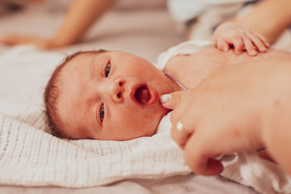 Woman's finger pulling down infant's lower lip